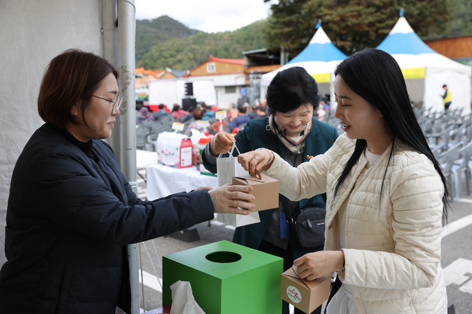 ▲ ‘우리술 푸드페어링’이 24일 오후 문경 가은아자개장터 일원에서 개막한 가운데 이벤트에 참가한 한 관광객이 기념품을 받고 있다.김영환 기자 yhk@kyongbuk.com