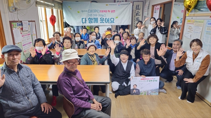 ▲ 의성군 정신건강복지센터와 방송인 한기웅 씨가 22일 의성군 후죽3리 마을회관에서 ‘찾아가는 재난 정신극복 프로젝트’ 순회공연을 열고 주민들과 함께 손을 흔들며 인사를 나누고 있다. 의성군