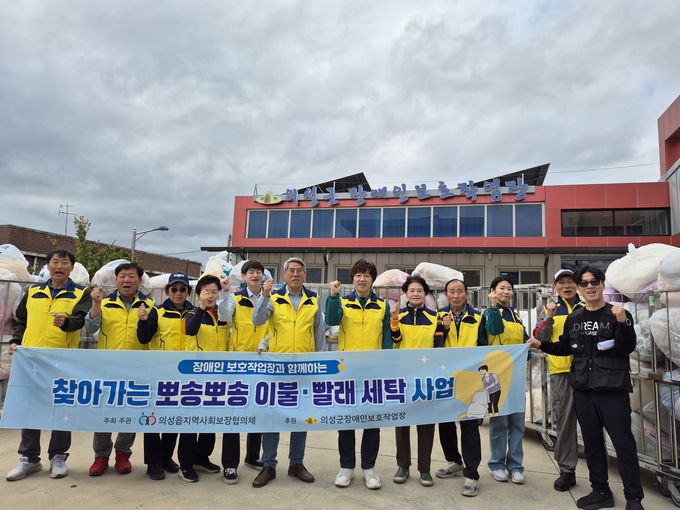 ▲ 의성읍지역사회보장협의체(위원장 조상칠, 왼쪽 여섯 번째) 위원들과 의성군장애인보호작업장 근로자들이 22일 의성읍 장애인보호작업장 앞에서 취약계층 80가구를 위한 ‘찾아가는 뽀송뽀송 이불·빨래 세탁사업’을 시작하며 구호를 외치고 있다. 의성군