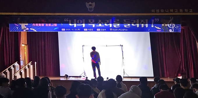 ▲ 의성유니텍고등학교 학생이 23일 교내 예공관 무대에서 열린 ‘너의 목소리를 들려줘!’ 사제동행 프로그램에서 조명을 받으며 노래를 부르고 있고, 객석의 학생들과 교사가 함께 박수로 호응하고 있다. 의성유니텍고