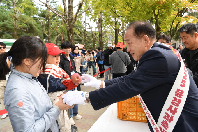 ▲ 2025 문경사과축제 대미를 장식하는 프로그램 일환으로 시민과 관광객들에게 사과를 나누어 주고 있는 신현국 문경시장.