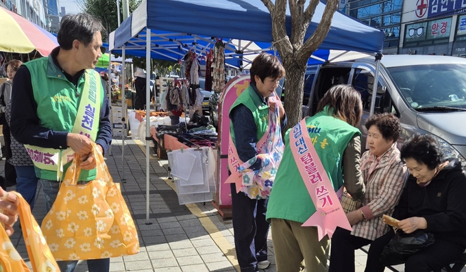 ▲ 27일 새마을 회원들이 공설시장에서 시민들에게 장바구니를 나눠주고 있다.  권오석 기자