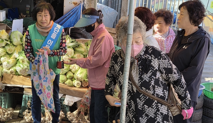 ▲ 27일 공설시장에 장을 보러 온 시민들이 새마을회에서 나눠주는 장바구니를 받기 위해 줄을 서 있다. 권오석 기자