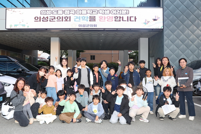 ▲ 의성도동·점곡마을학교 학생들과 교사들이 24일 의성군의회 청사 앞 전광판 아래에서 김미자 의성군의회 사무과장(오른쪽 첫 번째)과 함께 기념촬영을 하며 의정체험 프로그램 방문을 알리고 있다. 의성군의회