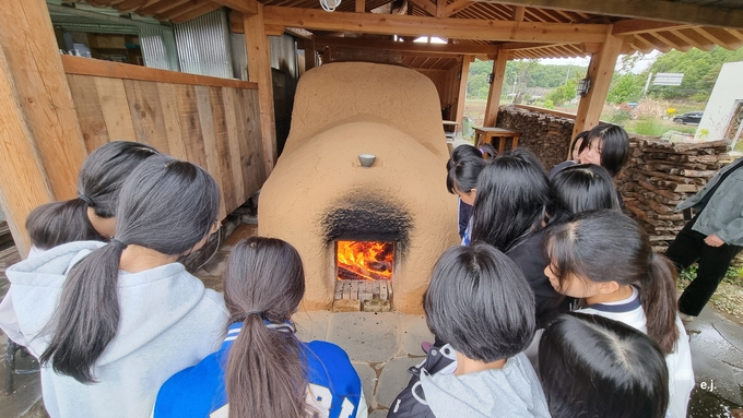 ▲ 탑리여자중학교 학생들이 24일 의성요 도자기공방의 전통 장작가마 앞에서 불길이 피어오르는 소성을 관찰하며 도자기 완성 과정을 배우고 있다. 경상북도의성교육지원청