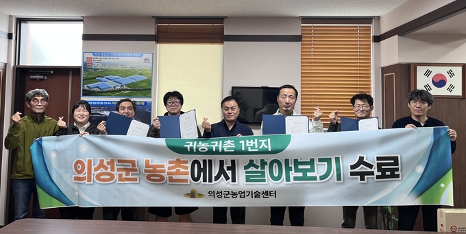 ▲ 박보근 의성군농업기술센터 지도관(왼쪽 다섯 번째)을 비롯한 관계자와 ‘농촌에서 살아보기’ 제3기 참가자들이 24일 의성군농업기술센터 회의실에서 수료증을 들고 단체 기념촬영을 하며 귀농·귀촌 체험형 프로그램의 수료를 축하하고 있다. 의성군