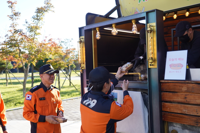▲ 경북소방본부 소방관들이 한국원자력환경공단이 진행한 APEC 히어로 응원 캠페인에서 핫도그를 수령하고 있다. 원자력환경공단