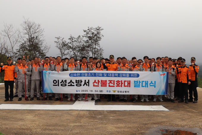 ▲ 의성소방서 소속 소방대원과 산불진화대원들이 24일 의성산불대응센터 헬기장 앞에서 발대식 현수막을 들고 주먹을 쥔 채 결의를 다지며 2025년 가을철 산불진화대 발대식을 진행하고 있다. 의성소방서