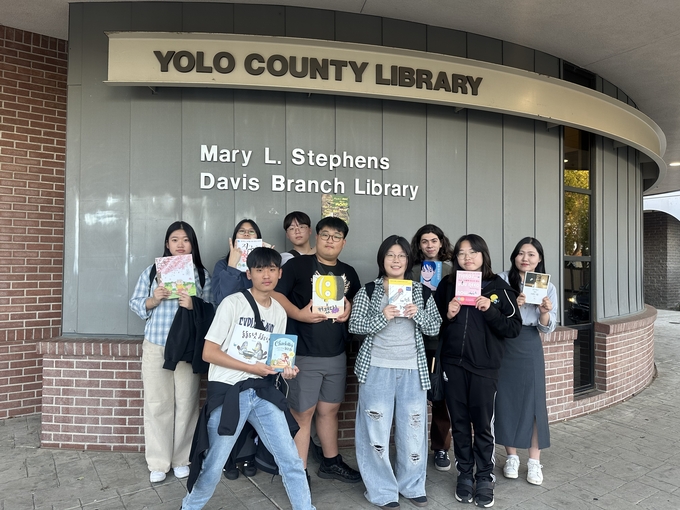 ▲ 지난달 24일부터 8박 10일 일정으로 진행 중인 ‘데이비스시 학생교류 홈스테이 프로그램’에 참여한 상주시 청소년들이 한글도서 기증 행사를 위해 준비한 책을 들고 도서관 앞에서 기념 촬영하고 있다. 상주시 제공