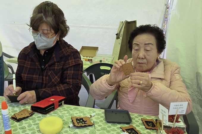 ▲ 어르신이 평생학습축제 체험부스에서 ‘나무로 만드는 별자리 무드등’을 만들고 있다. 권오석 기자
