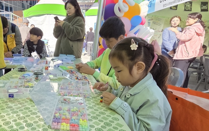 ▲ 어린이들이 평생학습축제 홍보 부스에서 비즈팔찌를 만들고 있다. 권오석 기자