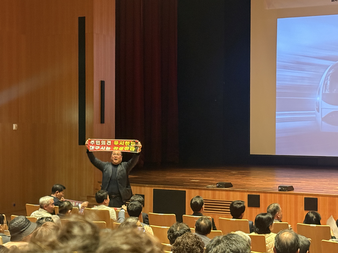 ▲ 지난달 31일 오후 북구 iM뱅크 제2본점에서 진행된 대구도시철도 4호선 주민설명회에서 한 주민이 현수막을 들고 항의하고 있다.  이유경 기자