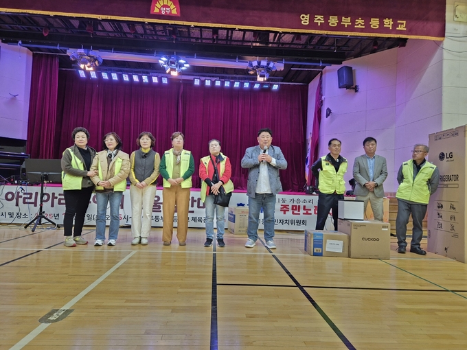 ▲ 영주시 휴천1동 주민자치위원회가 1일 동부초등학교 체육관과 원당천에서 ‘2025 휴천1동 어울림 마당’을 열고 있다. 신호철 주민자치위원장이 경품권을 추첨하고 있다