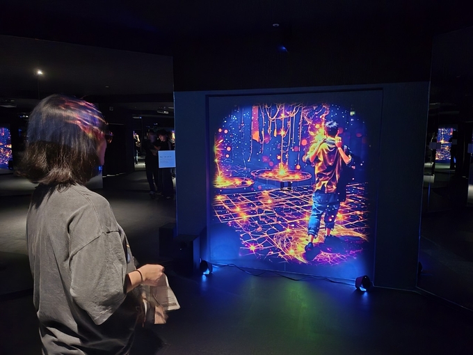 ▲ 경주 화랑마을이 지난달 23일부터 정식 운영하고 있는 ‘용화향도 시즌2’ 체험 공간에서 방문객이 AR그래픽과 실내 조명이 어우러진 몰입형 전시를 즐기고 있다. 경주시