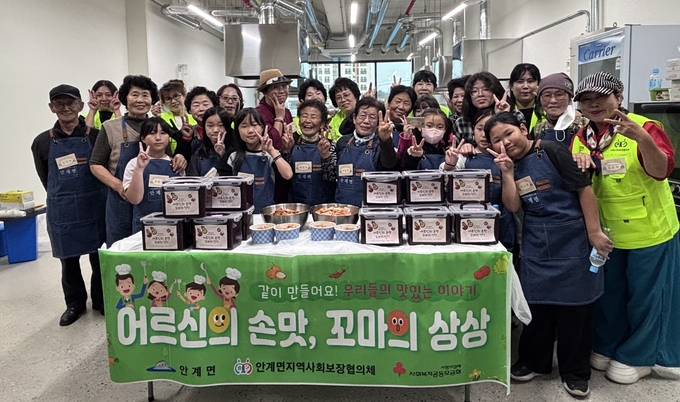 ▲ 6일 경북 의성군 안계행복플랫폼 공유부엌에서 열린 세대공감 프로그램 ‘어르신의 손맛, 꼬마의 상상’에 참여한 어르신과 아동, 안계면지역사회보장협의체 위원들이 김장 나눔을 마친 뒤 완성된 김치 상자를 앞에 두고 함께 기념촬영을 하고 있다. 의성군