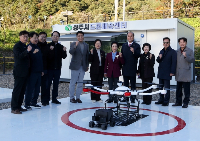 ▲ 상주시 경천섬 일원에서 ‘2025년 드론실증도시 구축사업(1단계)’ 성과보고회를 통해 드론과 로보가 연계된 입체적 무인배송 시연을 선보인 지난 10일 강영석 상주시장, 안경숙 상주시의회 의장(오른쪽·네번째부터), 시 관계자 등이 기념 촬영하고 있다. 상주시 제공