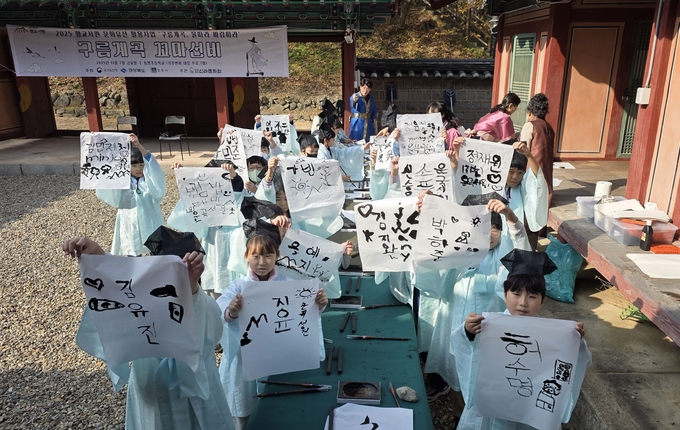 ▲ 신라문화원이 지난 7일 경주시 강동면에 위치한 운곡서원에서 진행한 ‘향교·서원국가유산 활용사업’에 참여한 동방초등학교 학생들이 직접 쓴 붓글씨를 들어 보이고 있다. 신라문화원