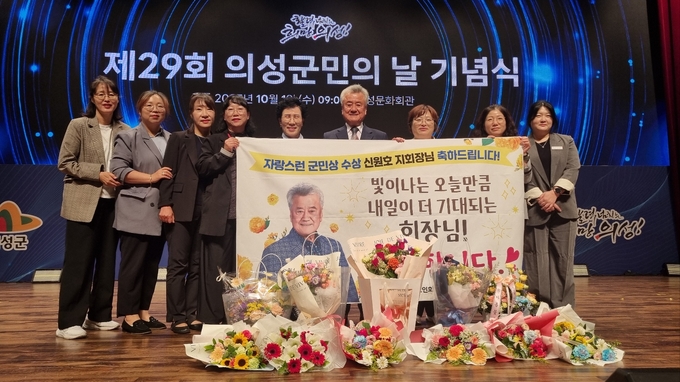 ▲ 제29회 의성군민의 날 기념식에서 ‘자랑스런 군민상’을 수상한 신원호 대한노인회 의성군지회장(왼쪽 여섯 번째)이 직원들과 함께 축하 현수막을 들고 기념촬영을 하고 있다. 대한노인회 의성군지회.