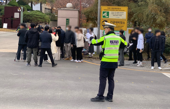 ▲ 13일 오전 포항고등학교  앞 시험장에 들어서는 수험생들의 안전통행을 위해 경찰관이 주행중인 차량에게 수신호를 하고 있다. 경북경찰청 제공