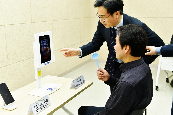 ▲ 경산시는 12일 시기능 보조기기 지원을 위한 ‘함께 보는 기쁨, 더 밝은 내일을 위한 빛나눔 전달식’을 가졌다. 조현일 시장이 시기능 보조기기 사용에 대한 설명을 듣고 있다. 경산시.