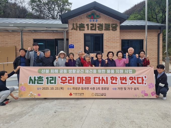 ▲ 10월 23일 의성군 점곡면 사촌1리 경로당 앞에서 산불 피해 복구 물품 지원을 받은 주민들이 새 생활공간 마련을 축하하며 현수막을 펼쳐 들고 단체로 재건 완료를 알리고 있다. 의성노인복지관