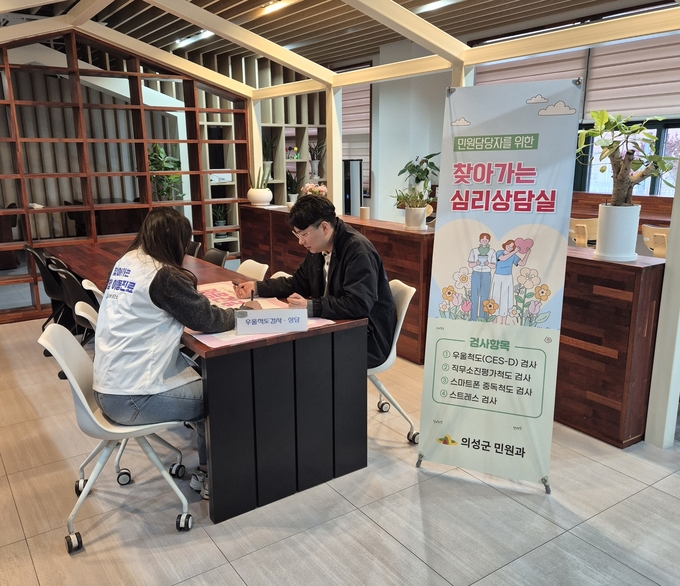 ▲ 17일 의성군청 내 휴게 공간에서 민원담당 직원이 상담원과 마주 앉아 우울척도 및 직무 스트레스 지표를 점검받는 가운데, 의성군 민원과가 운영한 찾아가는 심리상담실 안내 배너가 배치돼 현장 중심 심리지원 프로그램의 실제 진행 모습을 보여주고 있다. 의성군