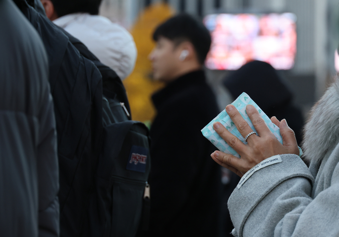 ▲ 서울 아침 기온이 올가을 처음 영하로 내려가는 등 한파가 찾아온 18일 서울 광화문 거리에서 한 시민이 핫팩을 들고 있다.연합