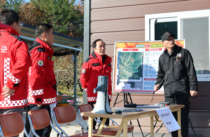▲ 17일 금성면 산불 모의훈련 현장에서 김주수 의성군수가 산불대책본부 관계자들과 함께 현장 지형도가 부착된 상황판 앞에 서서 지적봉으로 산불 확산 경로와 대응 동선을 짚어가며 실전 대응 계획을 점검하고 있다. 의성군