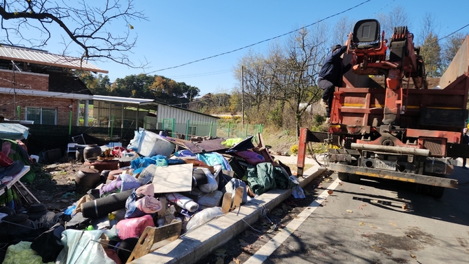 ▲ 문경시청년봉사단과 영순면행정복지센터 직원들이 저장강박증 가구를 방문해 트럭을 이용해 폐기물을 수거하며 주거환경을 정비하고 있다.