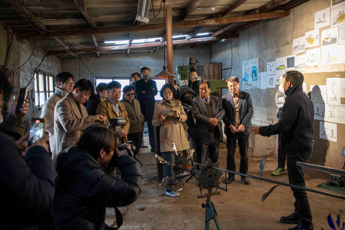 ▲ 18일 의성성냥공장 내 철공부에서 김진우 작가가 설치 작품 ‘숨쉬는 기계’를 시연하자, 벽면을 가득 메운 드로잉과 낡은 공장 설비를 배경으로 참석자들이 금속 장치의 움직임을 휴대전화와 카메라로 촬영하며 산업유산의 새로운 변신을 기록하고 있다 이정환 감독(포토그래퍼)