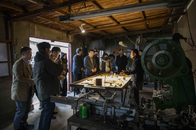 ▲ 18일 의성성냥공장 ‘요지부’에서 김진우 작가가 폐기된 성냥공장 기계 부품을 노란 페인트에 적셔 재구성한 설치작품을 통해 ‘녹슬고 부서진 도구에 새 불씨를 입혀 의성의 미래를 밝힌다’는 의미를 설명하자, 참석자들이 어두운 공장 공간과 밝게 비춘 작업대가 대비된 현장에서 작품의 상징성을 집중해 듣는 모습이다. 이정환 감독(포토그래퍼)