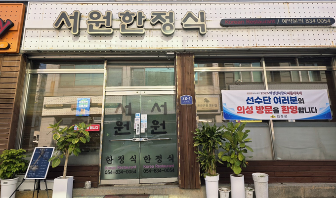 ▲ 23일, 의성읍 ‘서원한정식’ 건물 전면에 설치된 선수단 환영 현수막이 대회 분위기를 드러내듯 걸려 있고, 군 점검팀이 이를 중심으로 방문객 대응 준비 상황을 확인하고 있다. jhass80@kyongbuk.com