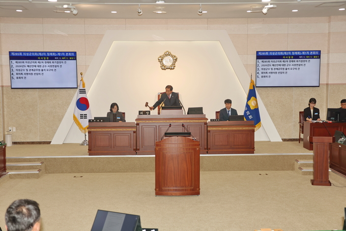 ▲ 24일 경북 의성군의회 본회의장에서 최훈식 의장이 제285회 제2차 정례회 1차 본회의 개회를 선언하며 의사봉을 두드리고, 집행부와 의원들이 정면 배석한 가운데 회의 화면에 안건이 공개되는 모습이 기록됐다. 의성군의회