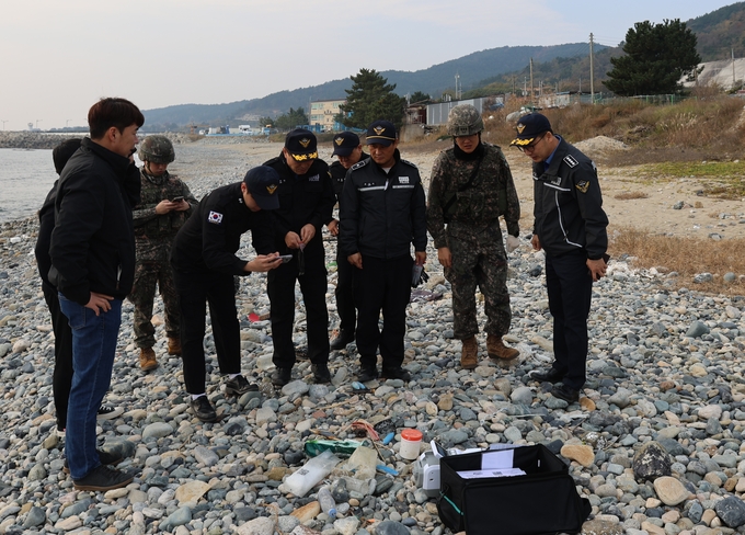 ▲ 영덕 백석 해변에서 발견된 마약 의심 물질을 해경이 살피고 있다.-울진해경 제공-