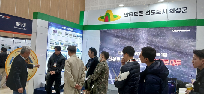 ▲ 18부터 20일까지 청주 오스코에서 열린 ‘2025 대한민국 대드론 박람회’ 의성군 홍보관에서 의성군 홍보대사 최영재(돌림판 오른쪽)가 방문객들과 안티드론 산업 전략을 설명받으며 부스 운영을 지원하는 모습. 의성군
