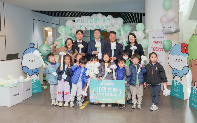 ▲ 25일 10만 돌파 기념행사에 참석한 ‘씩씩한 어린이집’ 원아들과 iM뱅크 관계자들 이 단체사진을 찍고 있다.